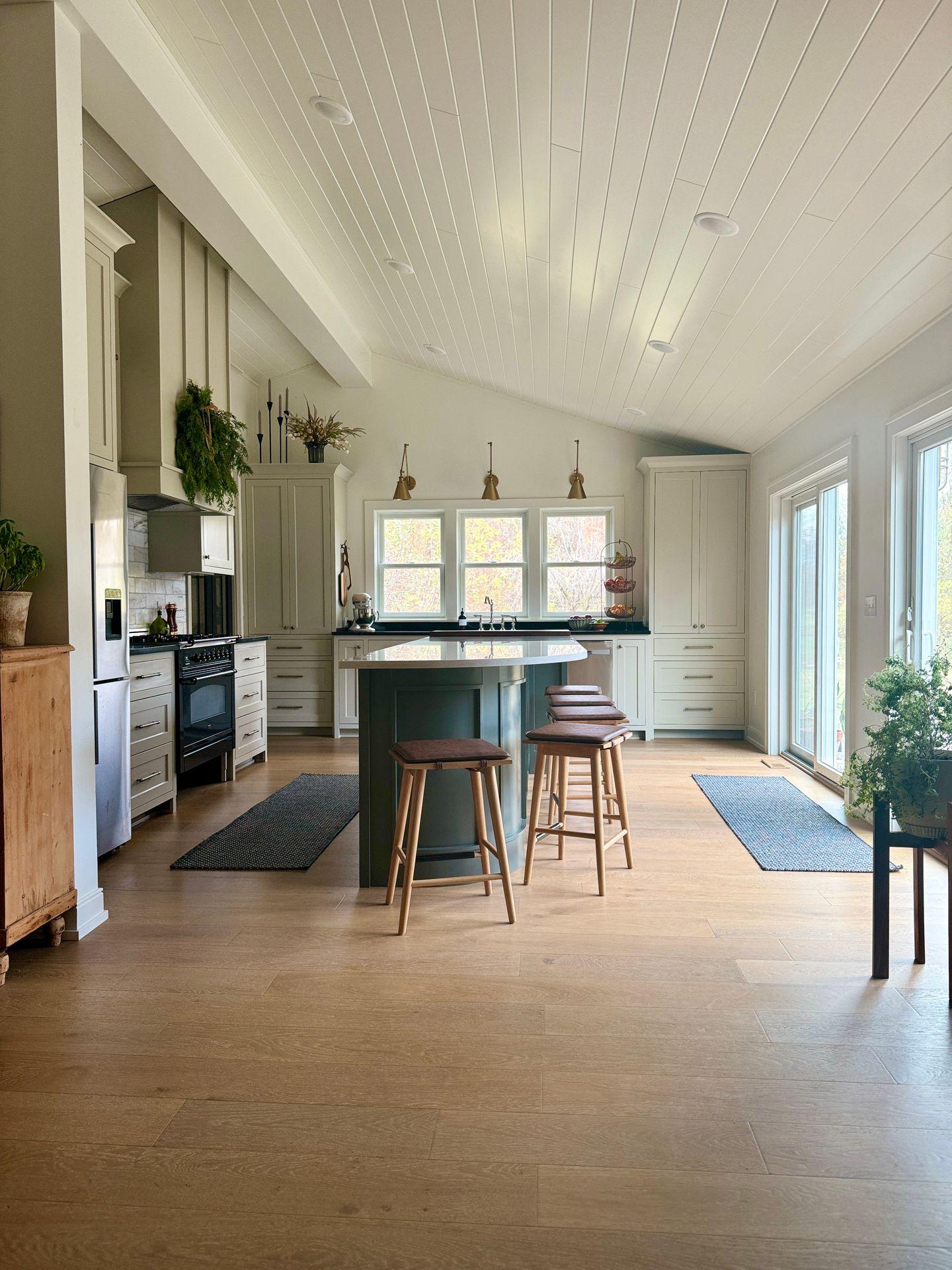 Spacious kitchen with a central island, stools, large windows, and modern decor.