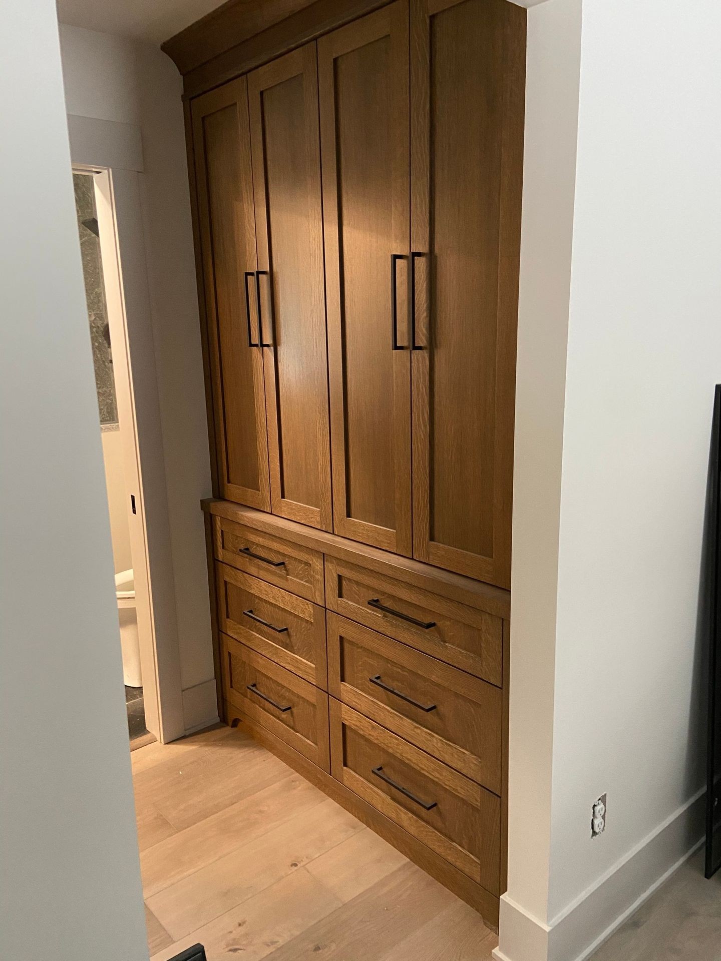 Wooden built-in wardrobe with multiple drawers and doors in a hallway.