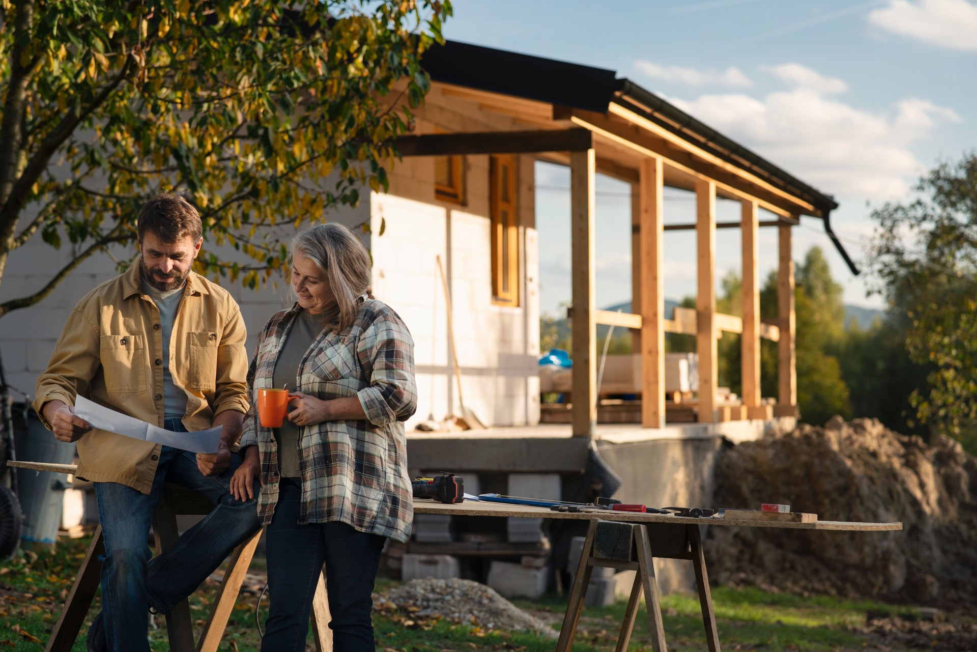 Mature couple having coffee break when working together on construction site of their new house.